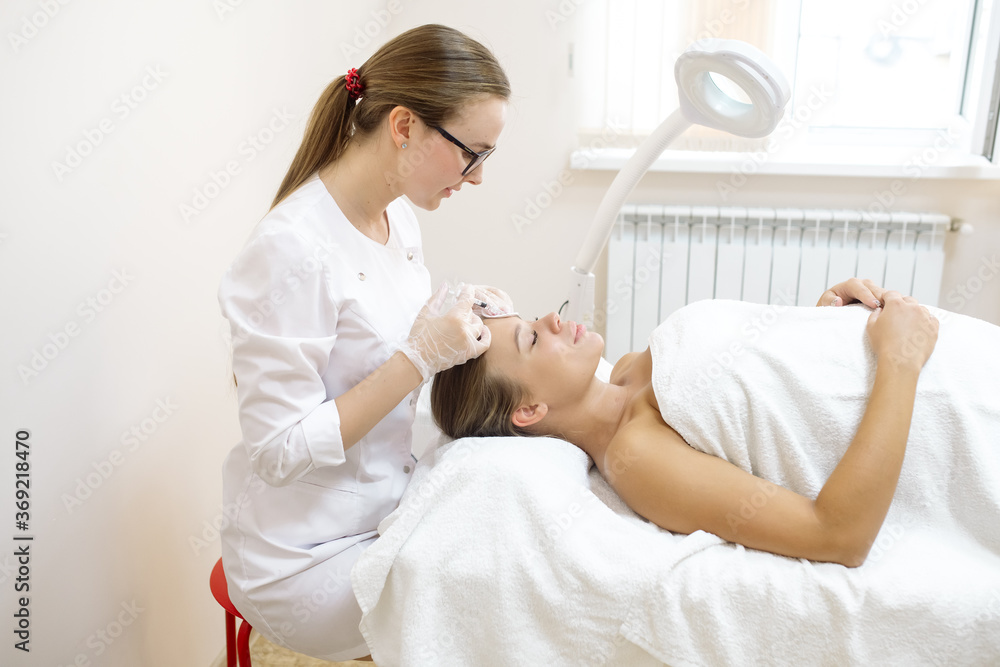 The beautician makes the patient injections and the forehead area during the procedure of mesotherapy and botox