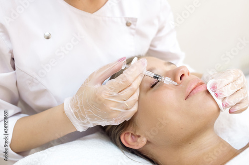 The beautician makes the patient augmentation of the lips with the help of injections of the hyaluronic acid filler
