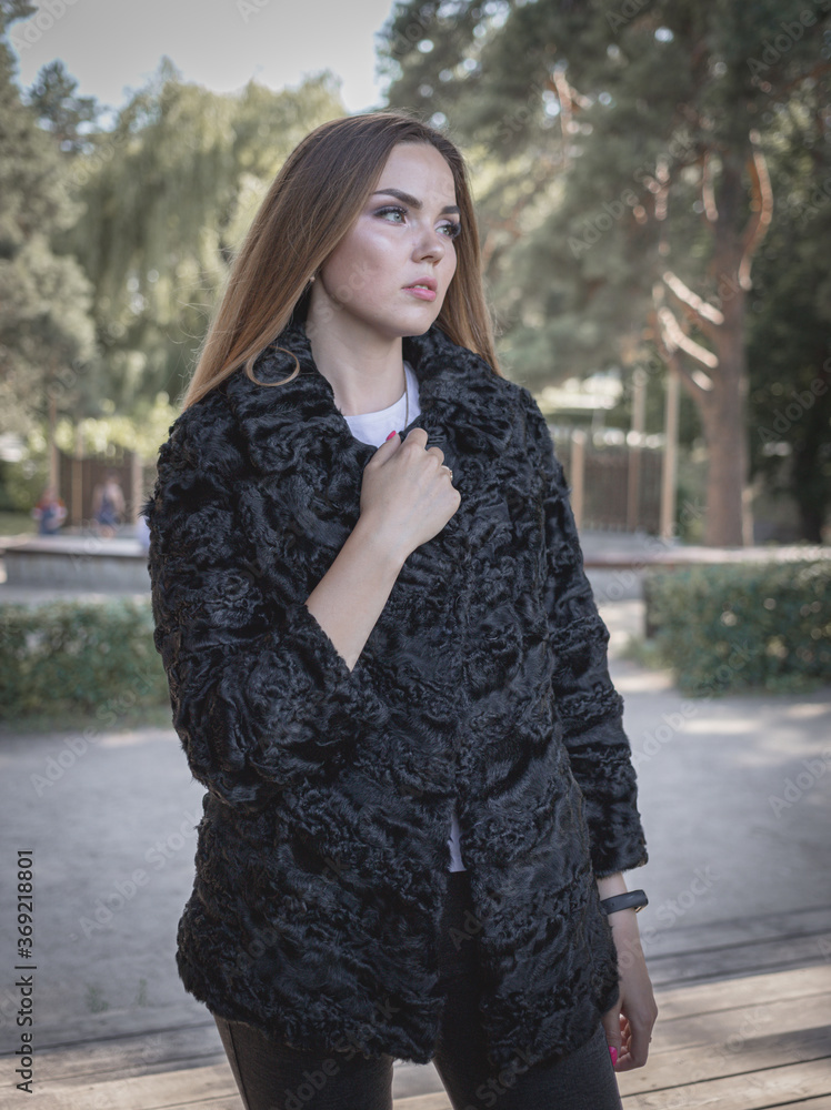 a beautiful girl with long hair and expressive eyes poses in a fur coat in a Park. High quality photo a beautiful girl with long hair and expressive eyes poses in a fur coat in a Park. High quality photo