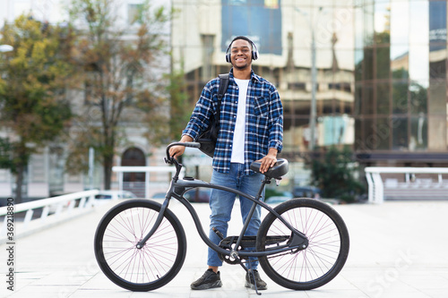 Portrait of african american guy standing with his bike