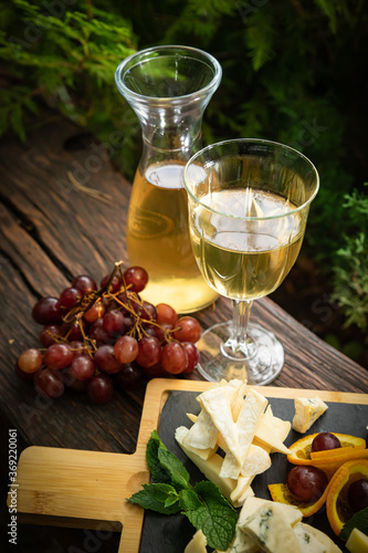Carafe with white wine on a wooden table. With a glass and a bunch of grapes 