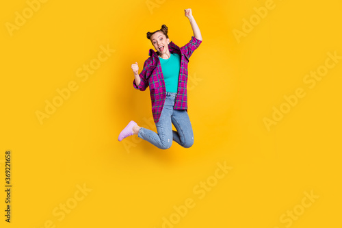 GOAL. Full size photo of attractive excited funky teenager lady jump up flight support sports team raise fists cheering wear casual plaid shirt shoes jeans isolated yellow color background