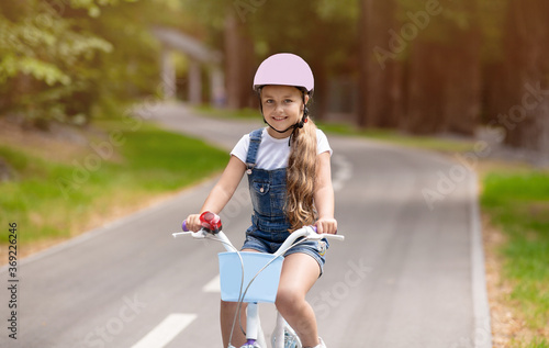 Carefree Kid Girl Riding Bicycle Outside, Wearing Protective Helmet