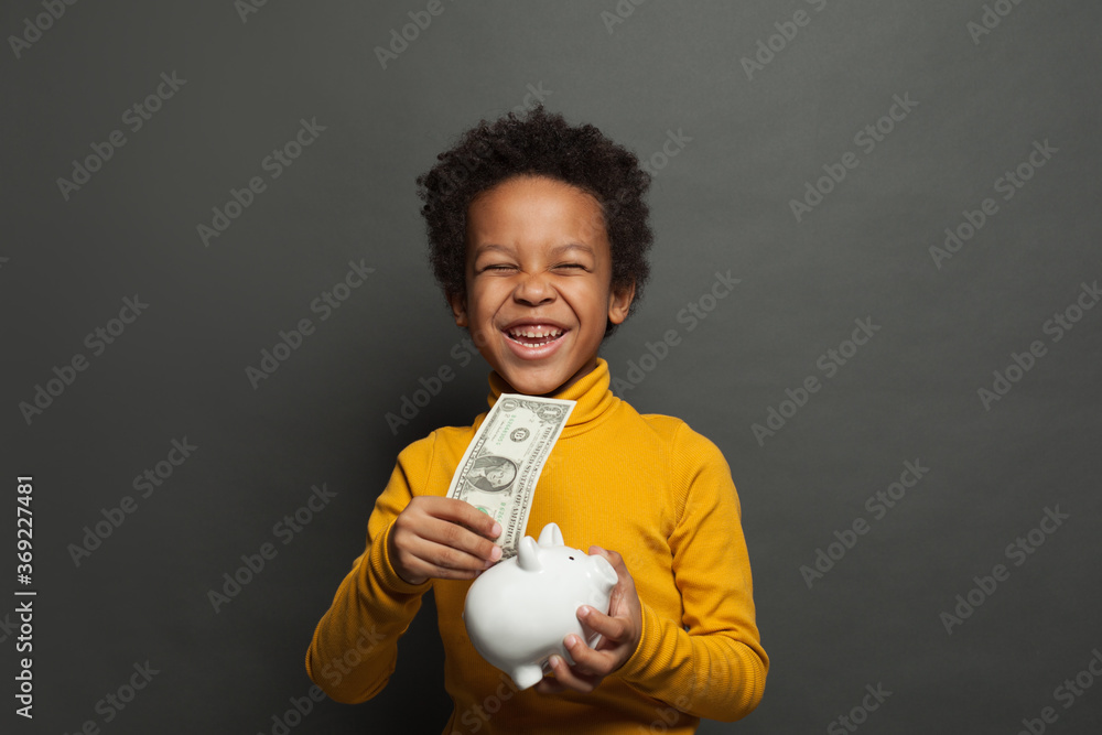 Laughing black child with money box and one us dollar on blackboard background
