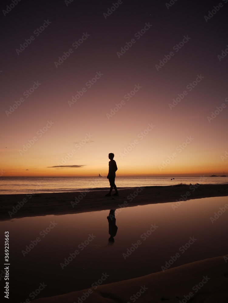 silhouette of a man walking on the beach at sunset silhouette of a man walking on the beach at sunset