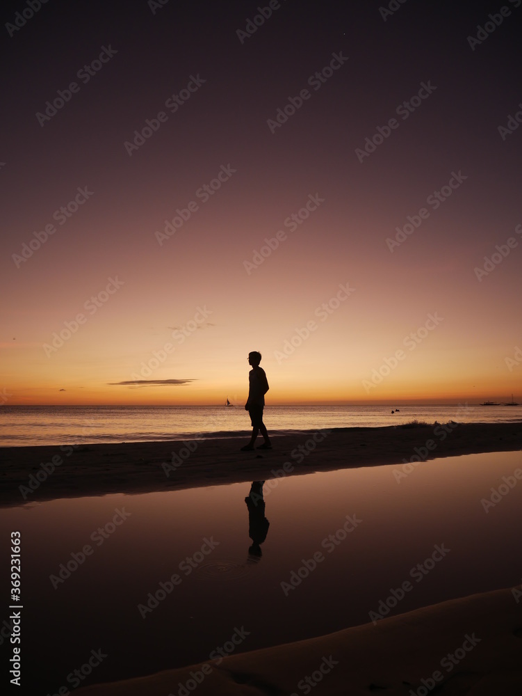 silhouette of a man walking on the beach at sunset