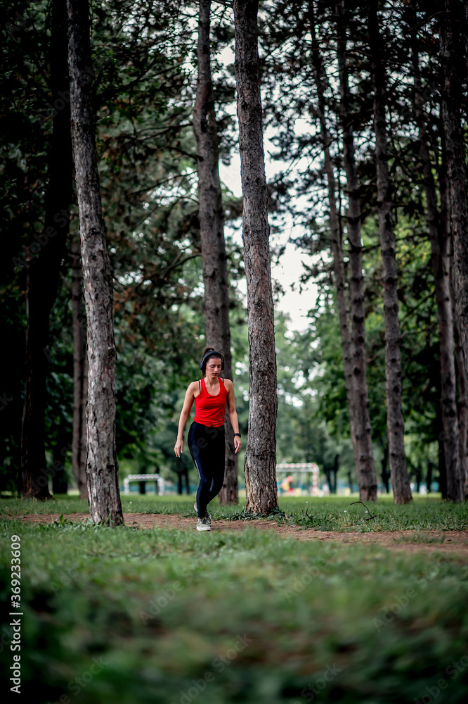 Obraz premium Young sporty woman jogging through the forest