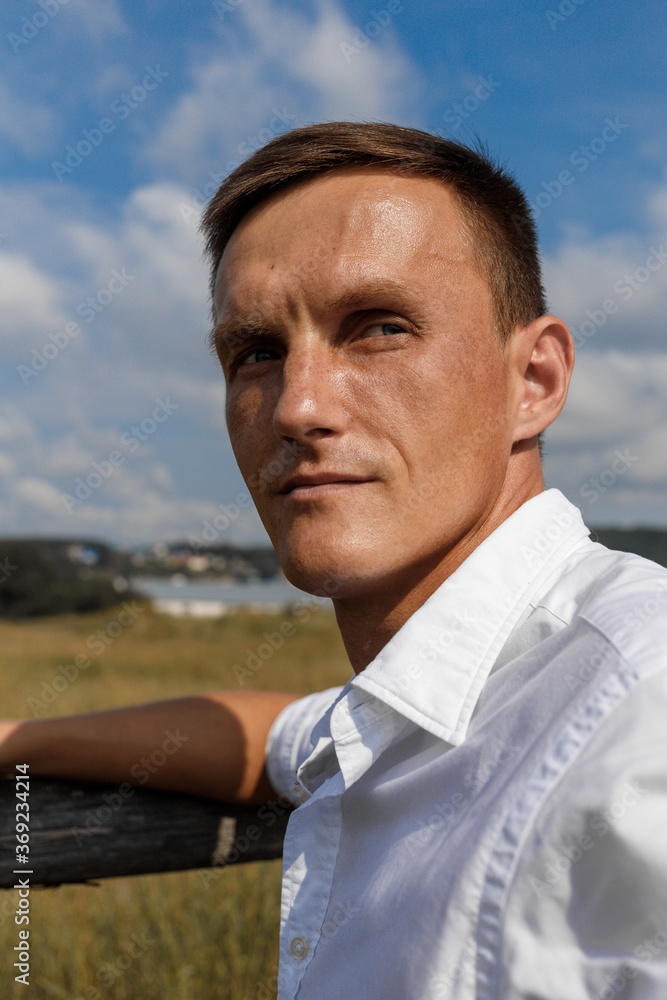 white urban handsome man of European appearance in a white shirt posing in the village. High quality photo white urban handsome man of European appearance in a white shirt posing in the village. High quality photo