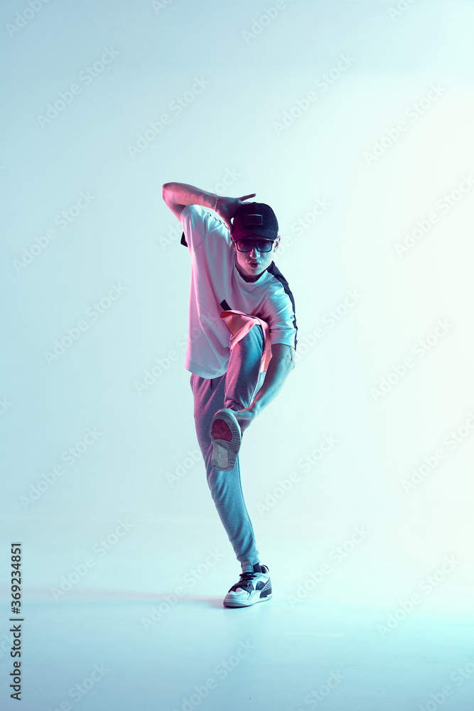 Young breakdancer guy in cap and sunglasses dancing hip-hop in neon light. Dance school poster