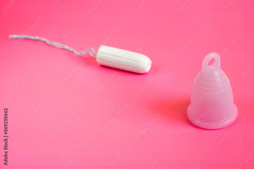 pink eco menstrual Cup and white tampon as methods of female hygiene during menstruation on a pink background