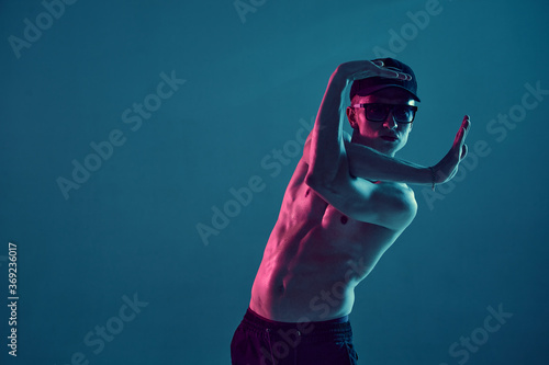 Cool young guy breakdancer dancing hip-hop without shirt in neon blue light. Dance school poster