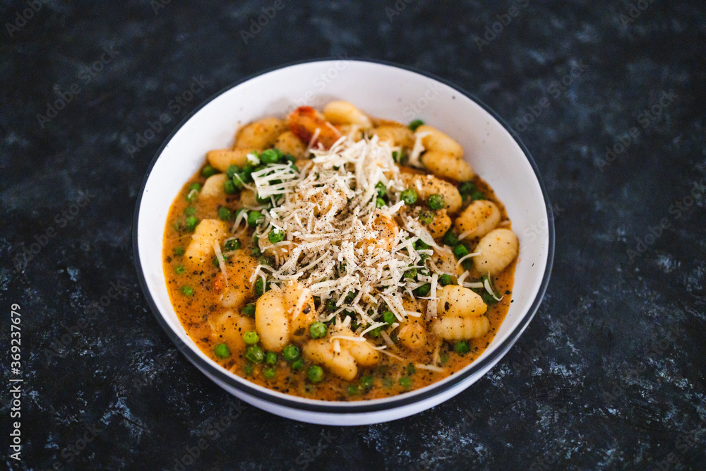plant-based food, vegan potato gnocchi with sundried tomatoes and peas in red pesto sauce with dairy-free cheese