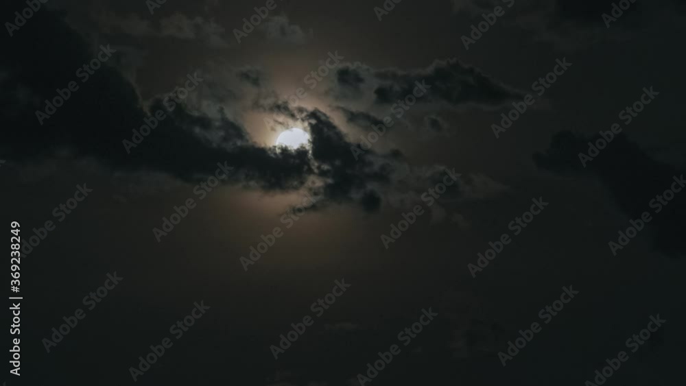 Full glowing yellow moon with clouds being blown by winds during storm at nights. Clouds passing by moon at night. Full moon at night with cloud real time. Full glowing yellow moon with clouds being blown by winds during storm at nights. Clouds passing by moon at night. Full moon at night with cloud real time.