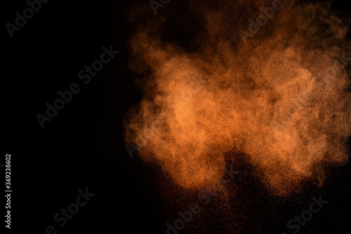 Orange powder explosion on black background. Colored powder cloud. Colorful dust explode. Paint Holi.