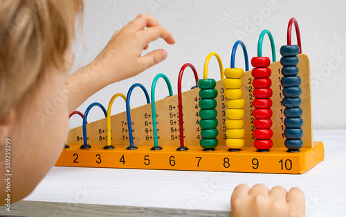 Abacus for children, learning mathematics and addition. Child playing with abacus on white table photo