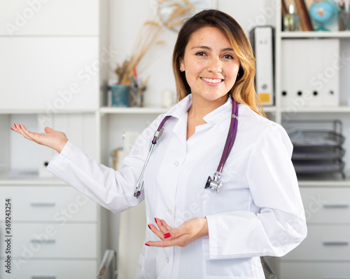 Smiling mexican female doctor in uniform inviting to doctor s office