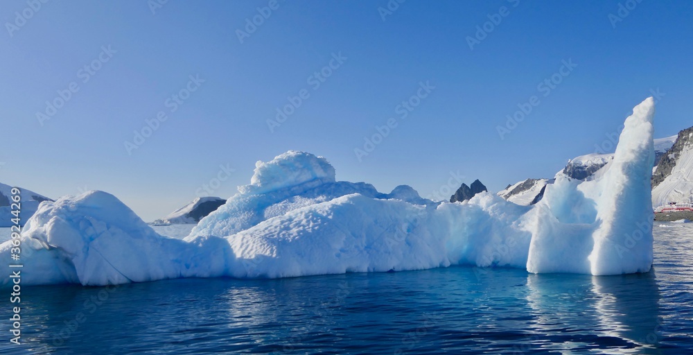 Blue iceberg in antarctic ocean, blue sky, bright sun, melting ice, Antarctica