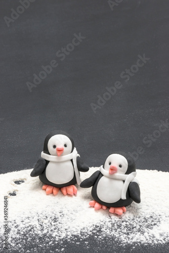zwei Pinguine aus Zucker im Schnee auf schwarzem Hintergrund
