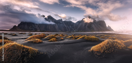 Stunning dramatic landscape image with cloudy mountain in Iceland during sunset. Impressive Colorful Seascape of Iceland. Wonderful picturesque Scene near Stokksnes cape and Vestrahorn Mountain