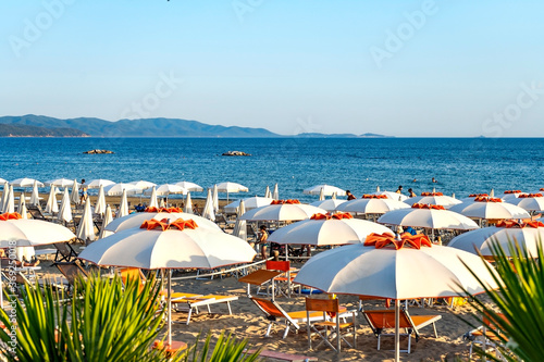 Fototapeta Naklejka Na Ścianę i Meble -  White and orange beach umbrellas in a bathing establishment in Pratoranieri, municipality of Follonica, Tuscany, Italy. Sandy beach and warm colors.
