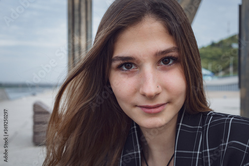 a beautiful young girl in a checked jacket and beige trousers poses for the camera in a Park. professional model with long hair. High quality photo Free Download a beautiful young girl in a checked jacket and beige trousers poses for the camera in a Park. professional model with long hair. High quality photo - GFXLoad