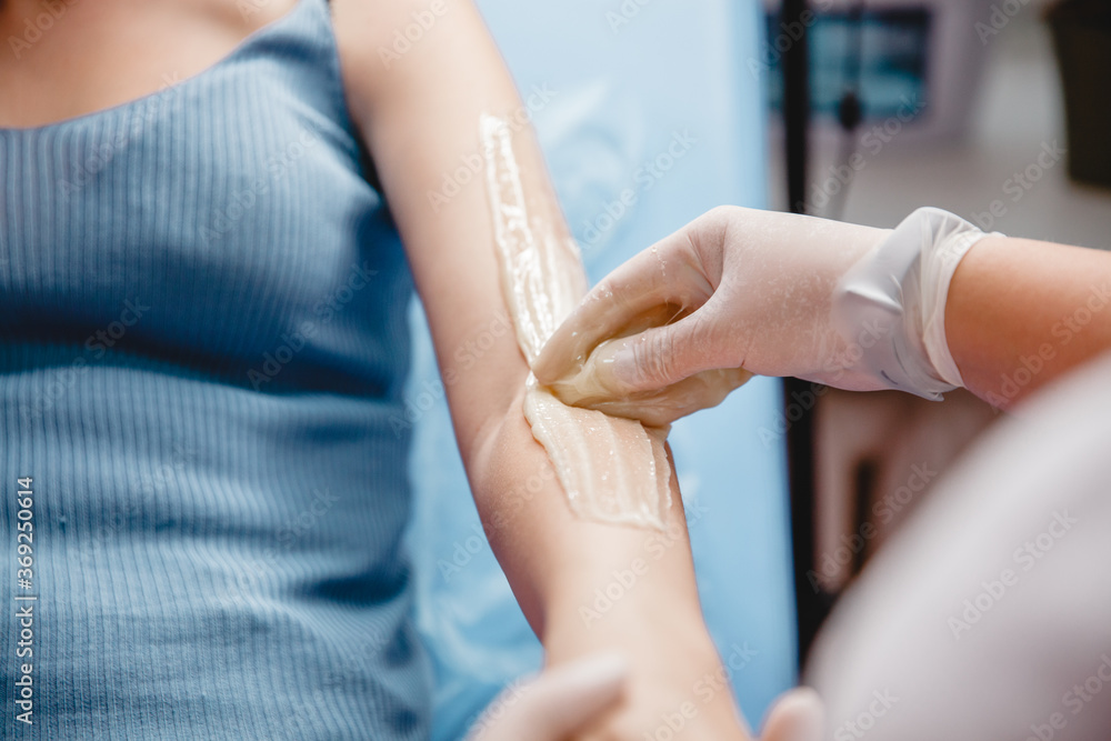 the master of sugaring puts paste on the client's hand in the salon the master of sugaring puts paste on the client's hand in the salon