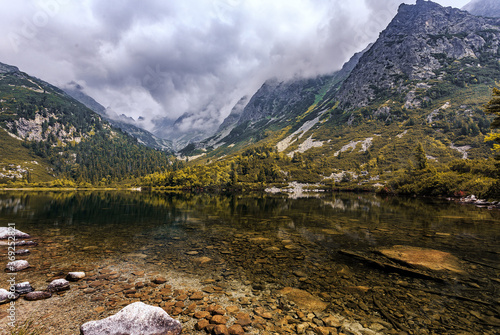 Beautiful nature Landscape. Alpine lake with colorful overcast sky and mountains. Incredible view of beautiful mountains in High Tatras. Magic Lake Popradske pleso, Slovakia. impressively Wild nature.