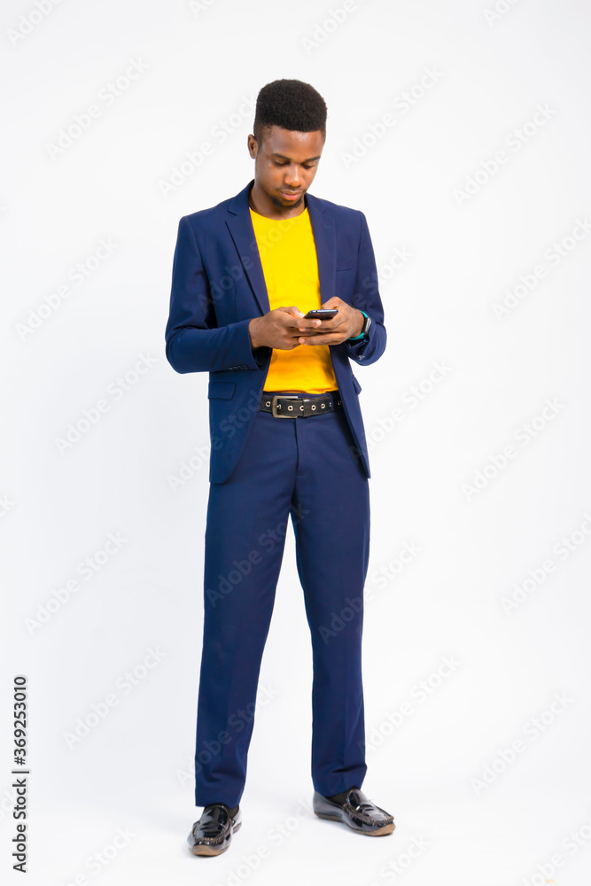 young black handsome man wearing a suit, holding his nose mask and using his smartphone young black handsome man wearing a suit, holding his nose mask and using his smartphone