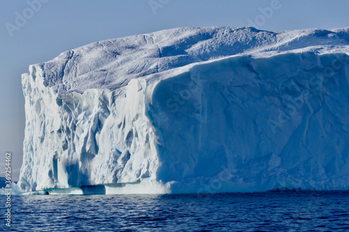 Blue iceberg in antarctic ocean, blue sky and sun, melting ice, Antarctica