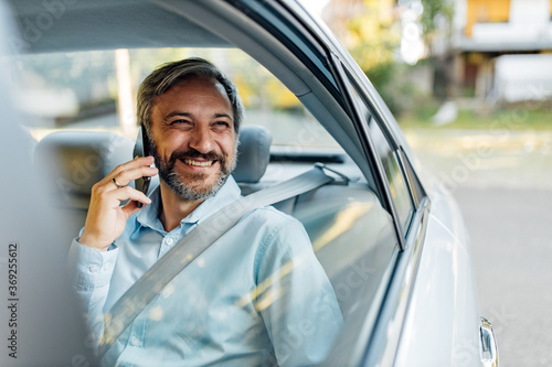 Happy man making a phone call in a taxi.