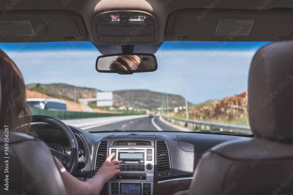Fototapeta premium The girl is driving on the road on Tenerife, Canary Islands. View from the back seat of the car on the windshield, road and the driver
