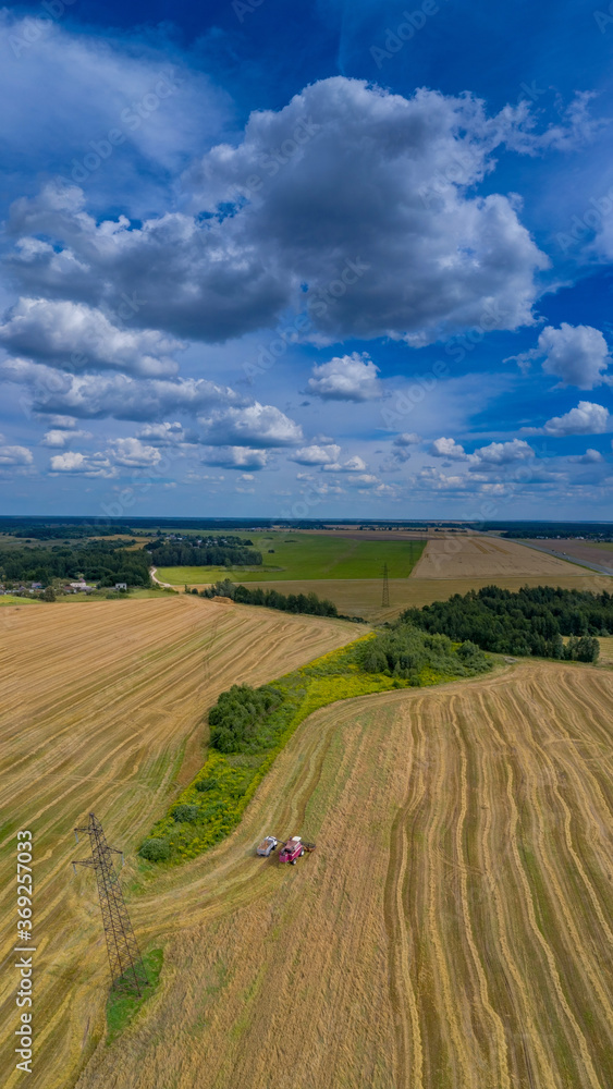 A colorful panorama from a 16x9 drone from four frames! Beautiful yellow fields and harvester and blue sky
