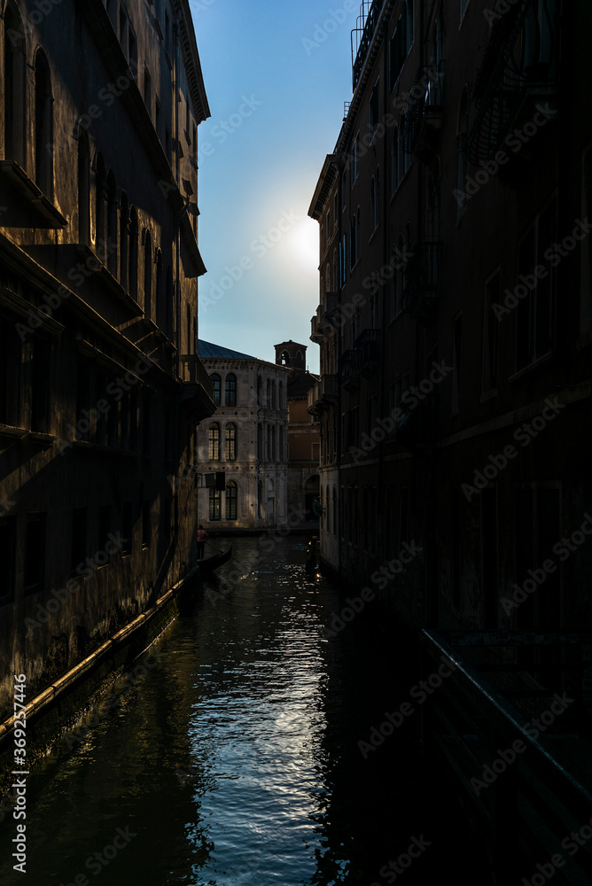 A lonely gondola navigating the water channeat sunrise near San Marco in the center of Venice