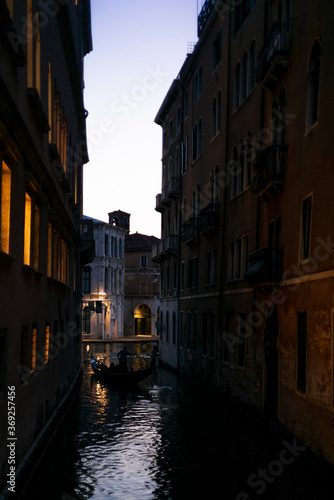 A lonely gondola navigating the water channeat sunrise near San Marco in the center of Venice