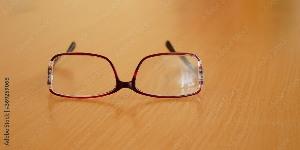 glasses with red frames lie on brown wooden table close glasses with red frames lie on brown wooden table close