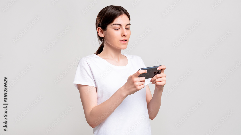 Online entertainment. Mobile app. Curious woman enjoying watching show on smartphone isolated on white copy space. Modern technology. Internet fun. Online entertainment. Mobile app. Curious woman enjoying watching show on smartphone isolated on white copy space. Modern technology. Internet fun.