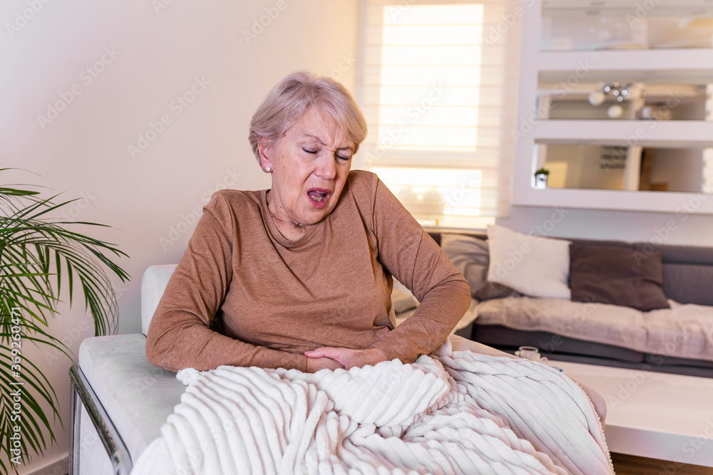 Old age, health problem and people concept - senior woman suffering from stomach ache at home. Senior woman suffering from stomach pain at home Old age, health problem and people concept - senior woman suffering from stomach ache at home. Senior woman suffering from stomach pain at home