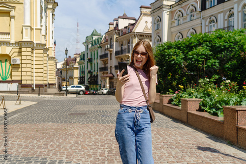 Beautiful Young Woman tourist in the City Center holding phone and making yes win gesture © Anatoly Repin