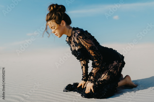 Woman sits in desert on white sand, relaxes and enjoys. photo