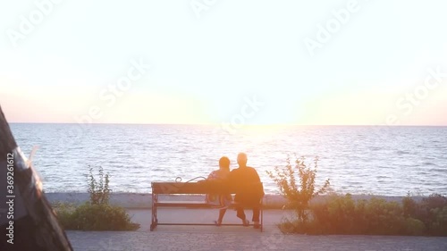 Elderly senior couple sitting on a bench by the sea or an ocean on vacation 