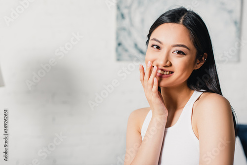 Beautiful asian girl smiling at camera at home