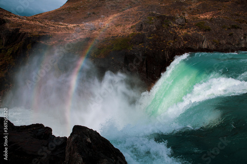 Scenic view of rainbow over waterfall flowing through rocks