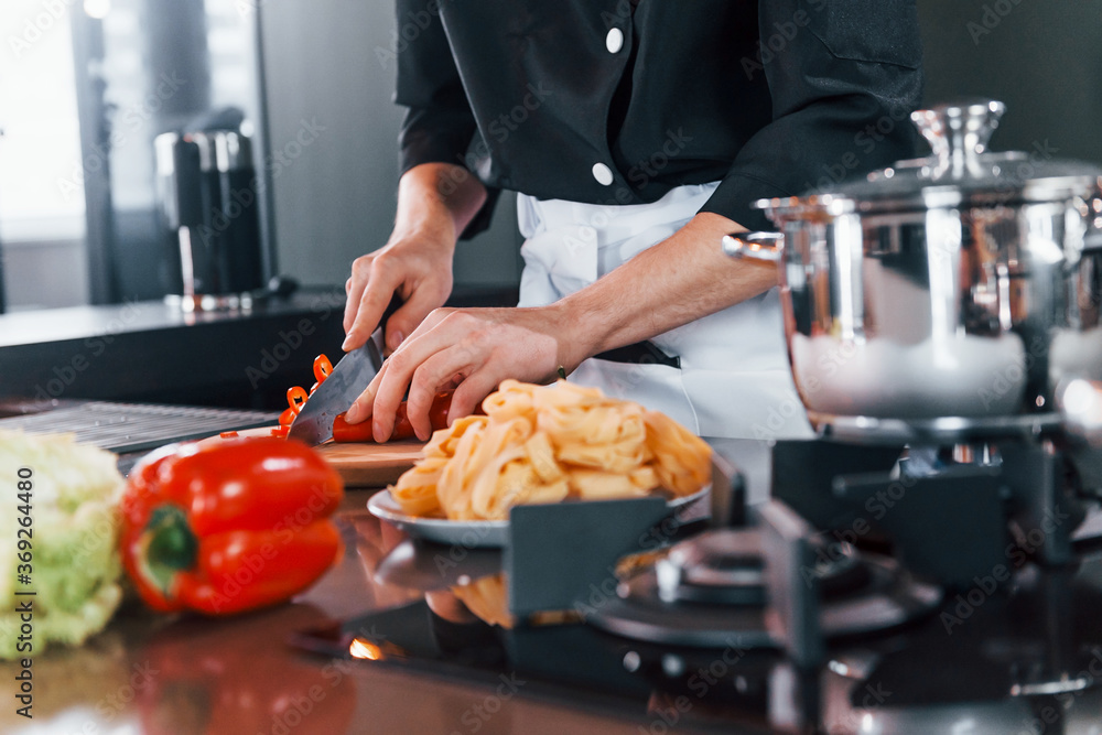 Close up view of professional young chef cook in uniform that working on the kitchen Close up view of professional young chef cook in uniform that working on the kitchen