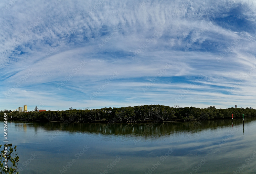 Beautiful panoramic view of a river with reflections trees, deep blue sky and rainbow look-alike clouds on water, Parramatta river, Rydalmere, Sydney, New South Wales, Australia

