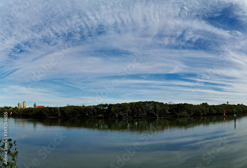 Beautiful panoramic view of a river with reflections trees, deep blue sky and rainbow look-alike clouds on water, Parramatta river, Rydalmere, Sydney, New South Wales, Australia
