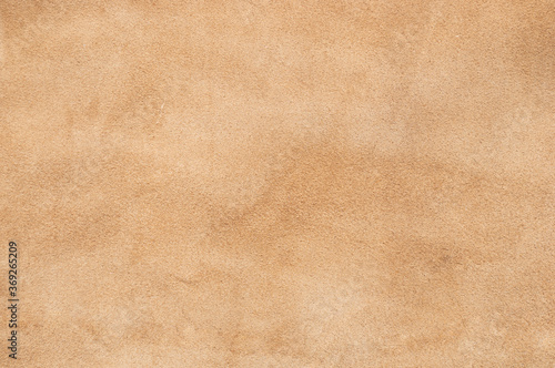 Light beige matte background of suede fabric, closeup. Velvet texture of seamless sand leather