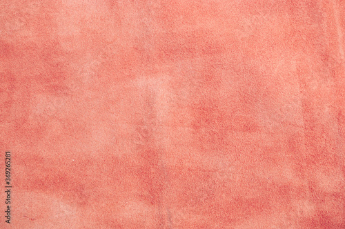 Light pink matte background of suede fabric, closeup. Velvet texture of seamless pastel leather.