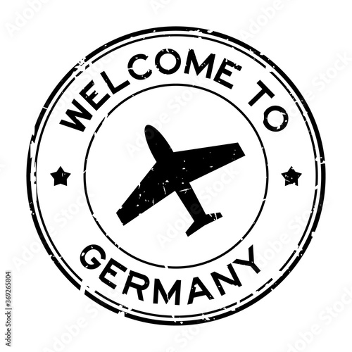 Grunge black welcome to Germany word with airplane icon round rubber seal stamp on white background