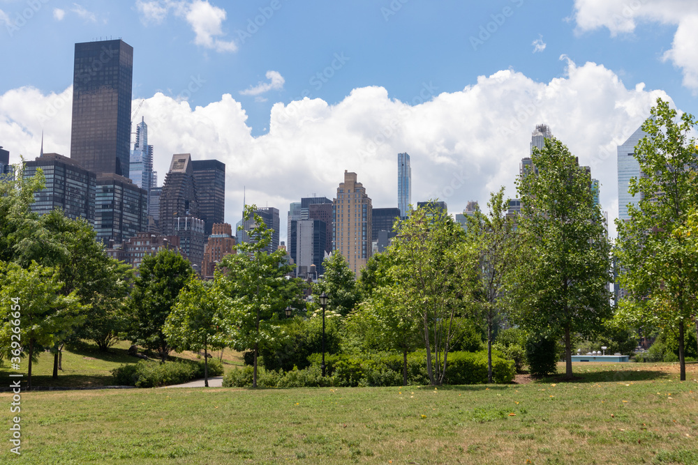 Fototapeta premium Green Grass Field at Southpoint Park with the Midtown Manhattan Skyline on Roosevelt Island during Summer in New York City