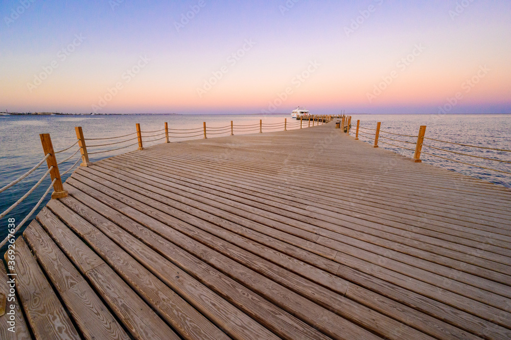 Wooden Pier on Red Sea in Hurghada at sunset and luxury yacht, View of the promenade boardwalk - Egypt, Africa